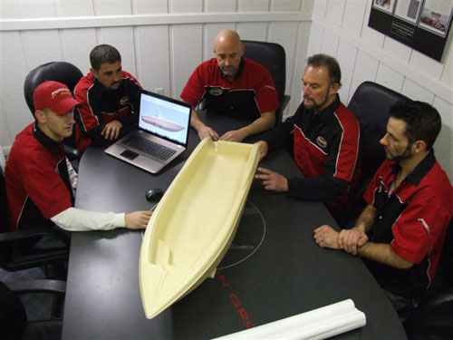 John Schaldenbrand (left), Joe and Wayne Schaldenbrand (center) and others on the Sunsation team examine a scale model of the company's upcoming 34-footer.